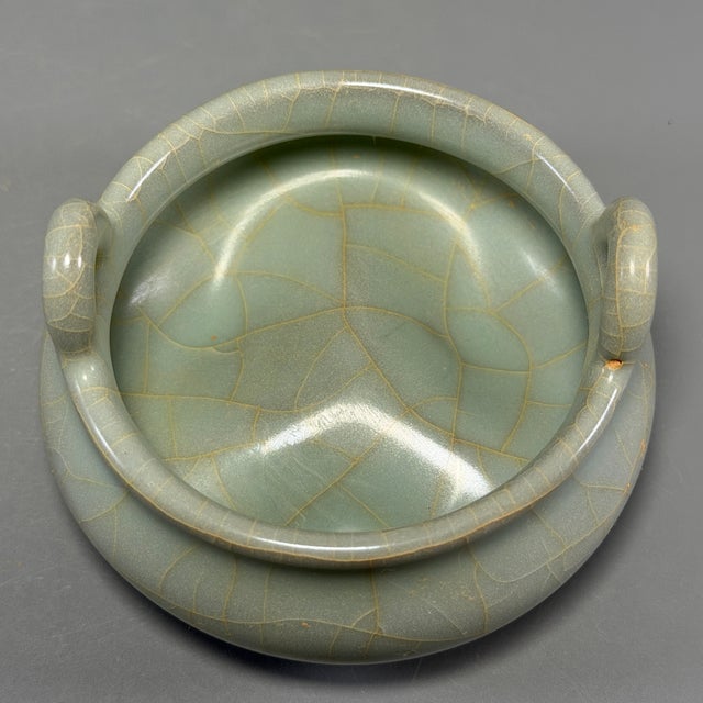 Classic Chinese official‑style celadon tripod censer, crafted with elegant upright loop handles, wide compressed body and...
