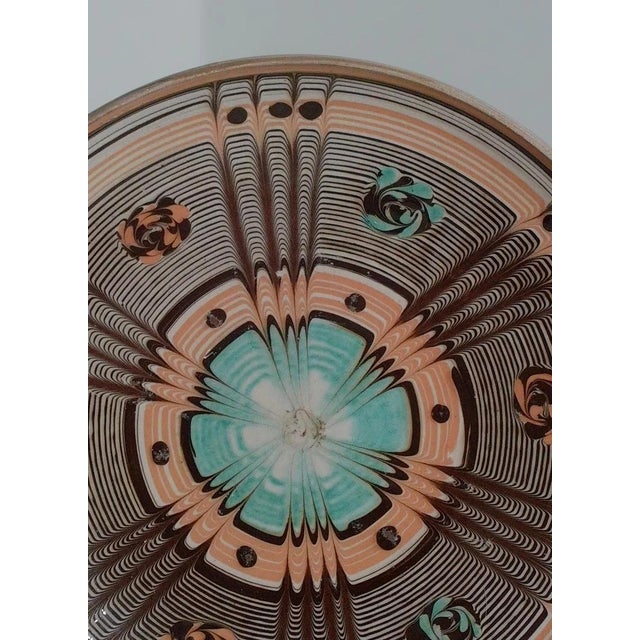 Vintage hand-painted ceramic plate featuring an intricate geometric sunburst design in turquoise, brown, and terracotta...