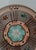 Vintage hand-painted ceramic plate featuring an intricate geometric sunburst design in turquoise, brown, and terracotta...