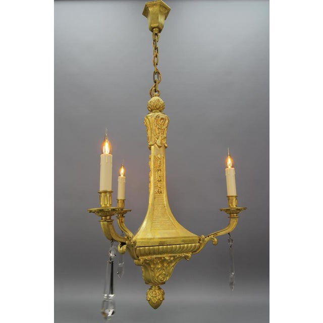 - French Louis XVI style bronze and crystal three-light chandelier from the early 20th century. - This impressive and...