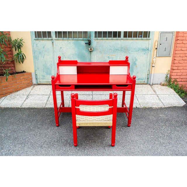 Desk with red lacquered wooden frame and formica doors. Chair with red lacquered wooden frame and straw seat. Cortina...