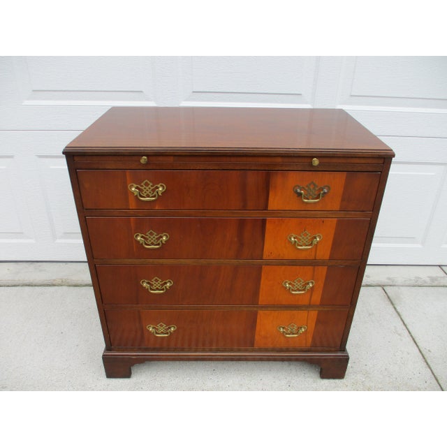 A classic four drawer Chippendale style chest of drawers with a slide-out tray by Baker Furniture. The chest sits atop...