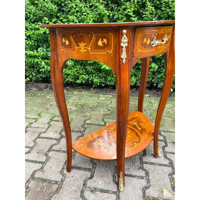 This refined French side table dates to approximately 1970 and reflects the elegant symmetry and restrained ornamentation...