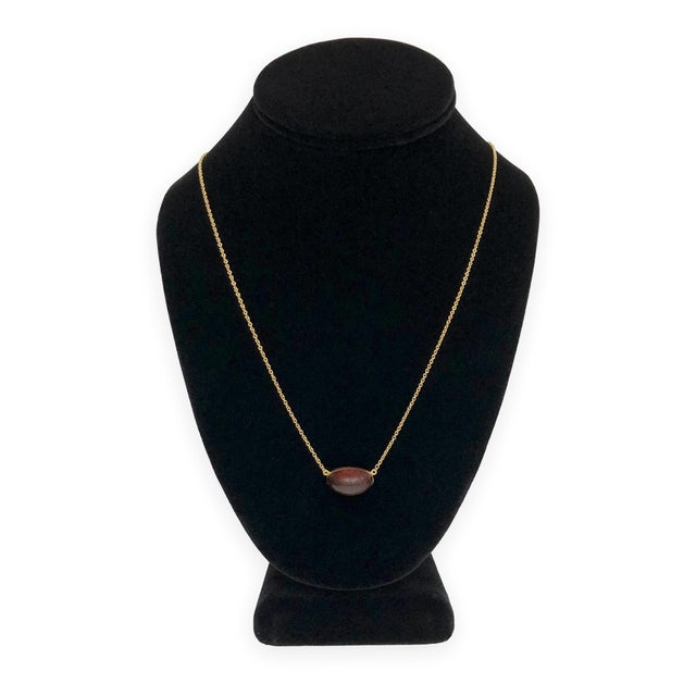 An Elsa Peretti pendant necklace with a freeform cabochon of natural amber in a warm orange-red hue, bezel-set in 18K...