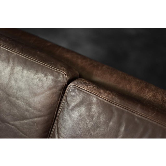 This wide three-seater sofa was made in Denmark in the 1970s. The modernist frame with six pillows is upholstered in...