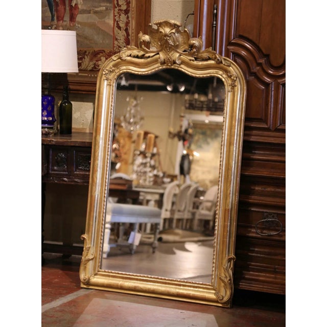 Standing nearly five feet tall, this antique mirror displays the graceful curves and elaborate ornament associated with...