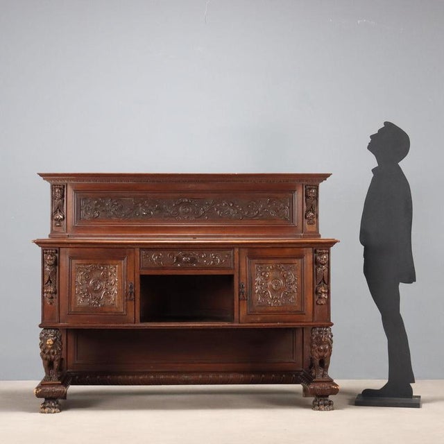 Neo-Renaissance-style walnut cupboard. Front with central drawer and side doors, supported by lion sculptures on a molded...