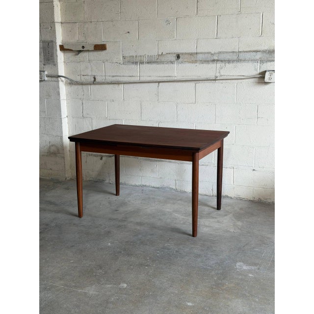 Beautiful vintage Danish modern dining table crafted in teak, featuring elegant minimalist lines, tapered round legs, and...