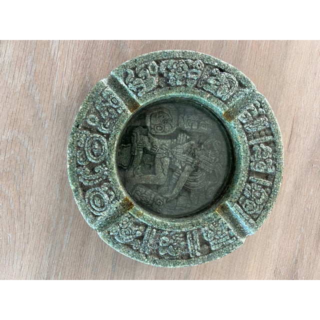 A vintage crushed malachite Aztec-style round ashtray with a glass center. Features a Quetzalcoatl or Mayan God motif in...