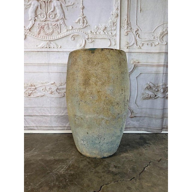 A beautiful terracotta vessel featuring a softly rounded, tapering form and a thick, hand-shaped rim. The surface presents...