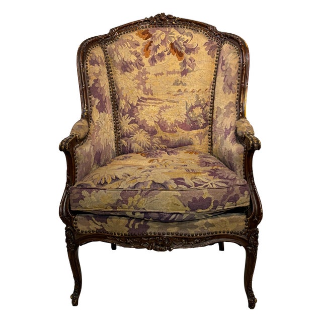 An extremely attractive bergere style armchair with antique tapestry upholstery. Elegantly carved wood frame with remnants...