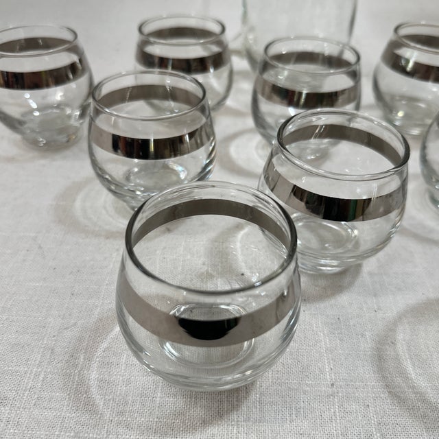 Up for consideration is a beautiful collection of small glasses and a matching pitcher with silver accents. These would...
