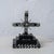 A Haitian Vodou cross for Baron Samedi, carved and painted black with white detailing, on a three-tier stepped base. A...