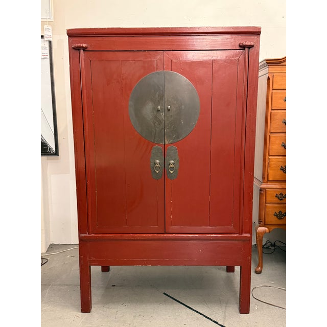 Design Plus Gallery presents a Chinese Wedding Cabinet from the Early 20th Century. The cabinet has a red lacquer stain...