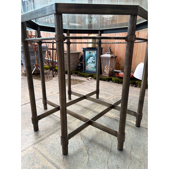 A striking vintage dining table featuring an octagonal glass top with beveled edges, set on a sculptural metal base with...