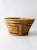 This is a vintage basket bowl. The handwoven woven basket features a decorative pattern in browns and black.