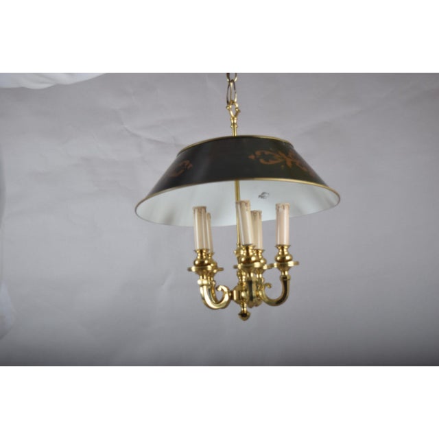 A striking bouillotte-style hanging chandelier, combining a warm brass six-light frame with a classic painted tôle shade....