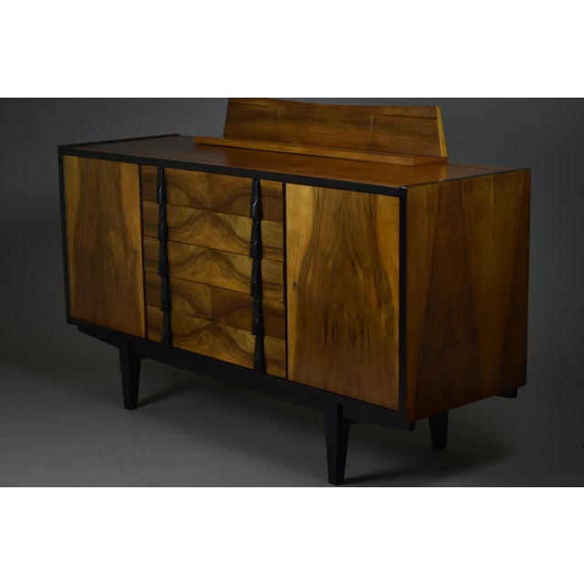 This elegant mid-century modern sideboard was designed in Poland in the 1960s. It features a beautiful walnut veneer with...