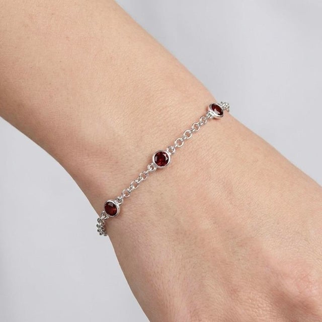 Refined and timeless, this elegant bracelet showcases the deep allure of rich red gemstones delicately set along a sleek...