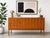 Mid Century Modern teak credenza sideboard featuring striking wood grains and a thoughtful layout. This elegant piece...