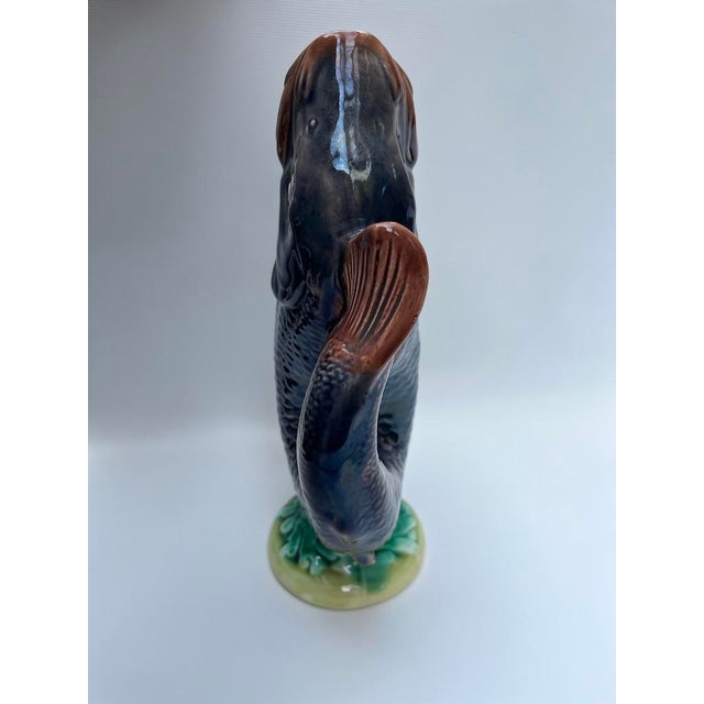 A single antique majolica pottery fish shaped gurgle jug or pitcher with tail handle with multicolor glazed decoration.