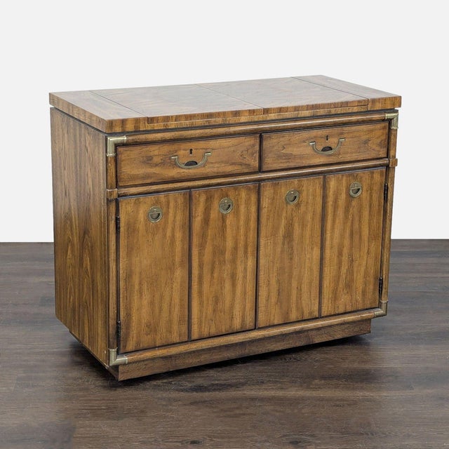 Produced in the 1970s, this piece features warm fruitwood and campaign-inspired brass accents. Two concealed flip-top...