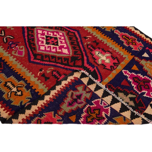 Beautiful vintage Turkish Kilim hand-knotted wool rug with a red field. This piece has a navy blue frame and multicolor...