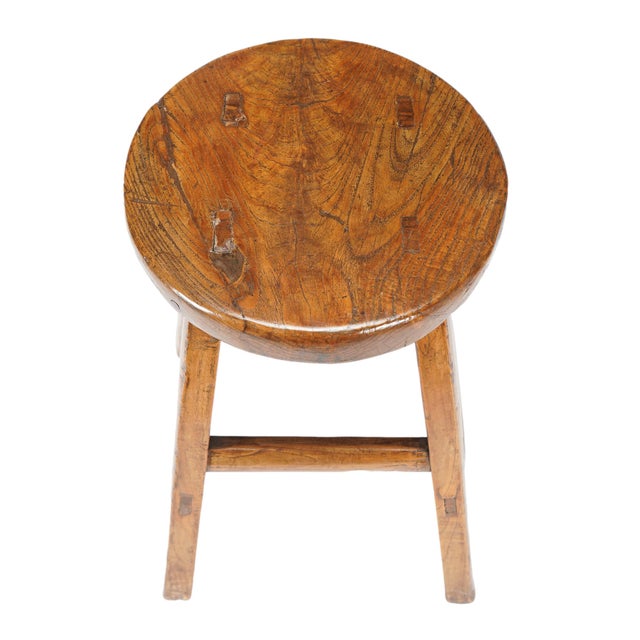 A late Qing Dynasty elm stool from China, dating to 1875-1900, with a broad circular seat raised on four square, gently...