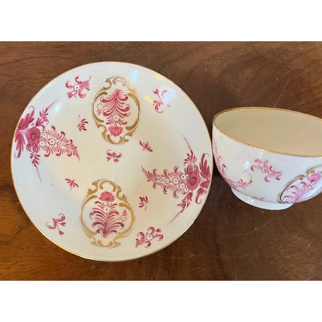 Antique 18th century German porcelain handleless cup and saucer. Decorated with puce flowers enhanced by rich gilding....