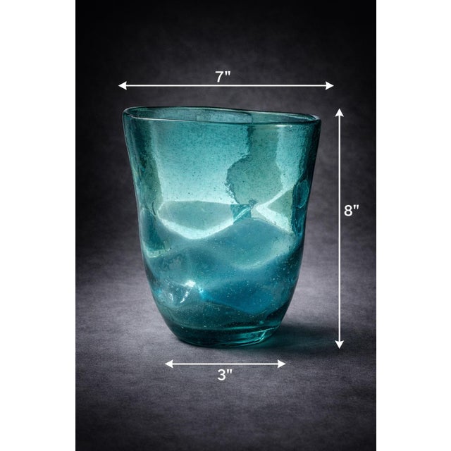 A beautifully fluid hand-blown aqua art glass vase featuring an organic, softly wavy silhouette and luminous blue-green...
