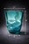 A beautifully fluid hand-blown aqua art glass vase featuring an organic, softly wavy silhouette and luminous blue-green...