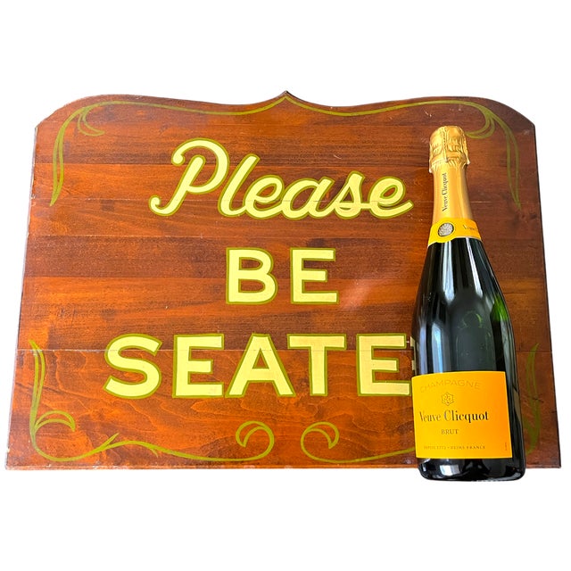 A welcoming “Please Be Seated” sign painted on a substantial solid wood panel. Cream lettering outlined in olive green...