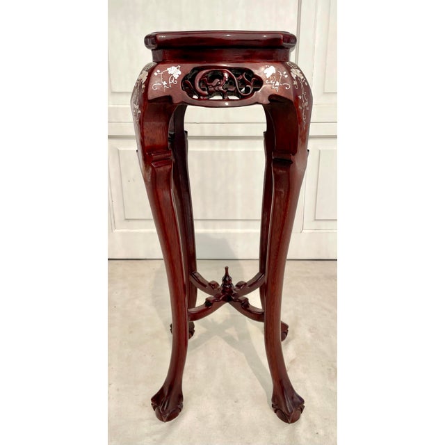 This vintage Chinese pedestal stand features a rich rosewood finish, intricate mother-of-pearl floral inlay, and elegant...