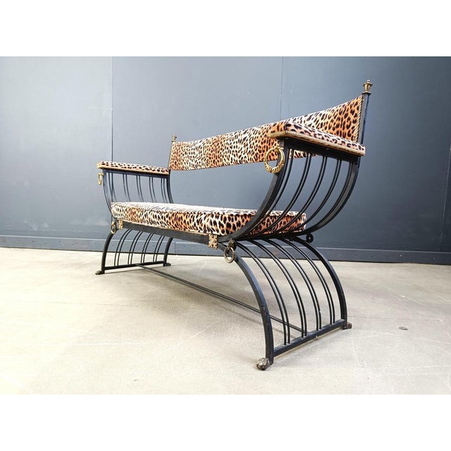 Fantastic Hollywood regency 'curule' bench made from black wrought iron and with brass details. Brass claw feet and rings....