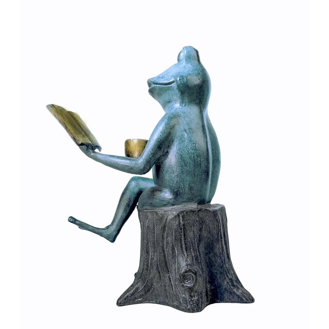 Whimsical sculpture of frog on tree stump with a cup of coffee and reading a book! Coffee cups says "Coffee makes me hop"...