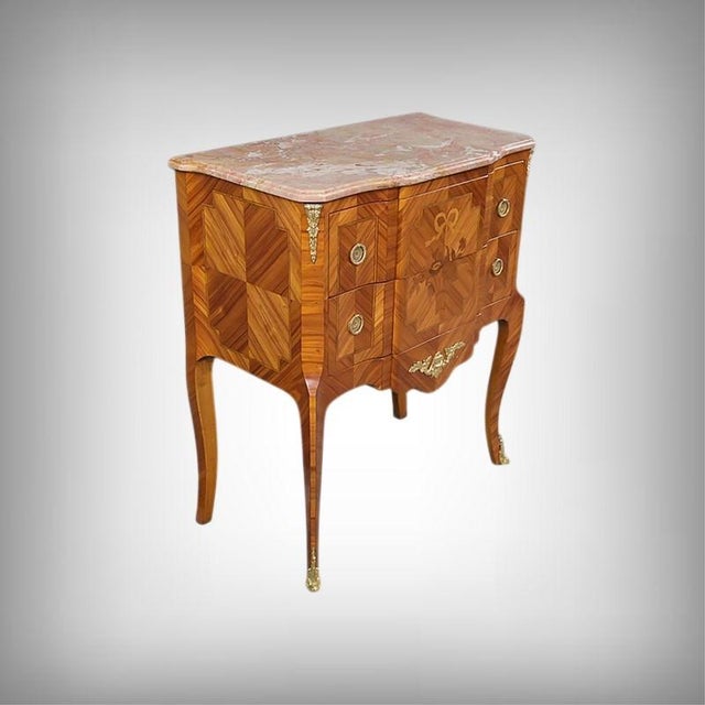 This marquetry commode elegantly embodies the spirit of the transition style, a period when the sensual curves of louis xv...