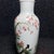 This elegant vintage porcelain vase features a classic bottle form with a tall, slender neck. The body is finely hand-...
