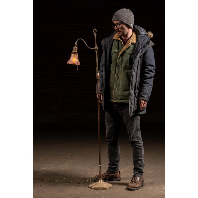 Early electric floor lamp featuring a slender brass standard rising from a stepped round base. The upper section is fitted...