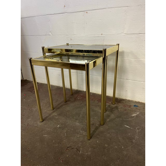 Beautiful simplistic brass plated nesting tables with smoke glass. In the manner of Belgo-Chrome. Sleek lines for subtle...