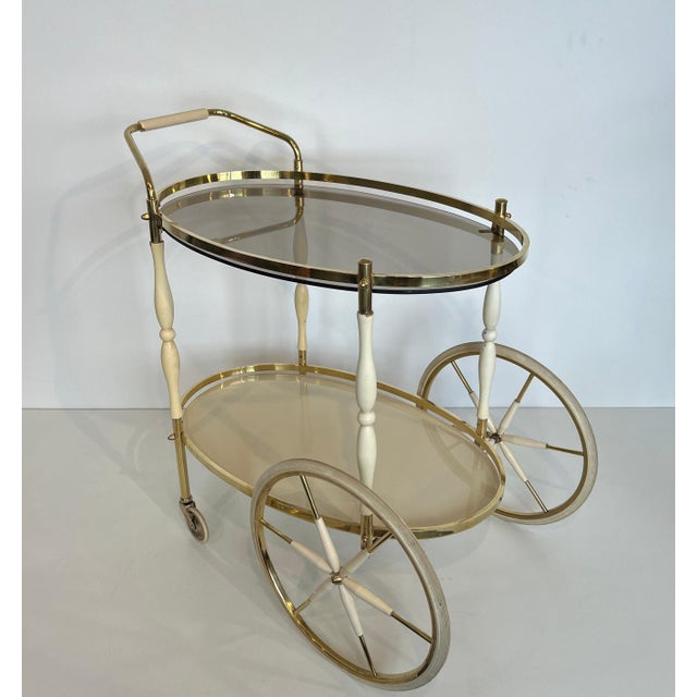 This beautiful oval bar cart with an elegant design is made of brass and lacquered wood. It is an Italian work. Circa 1940