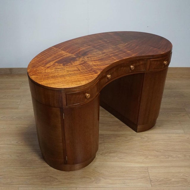 An early 20th century kidney shaped desk. Flame mahogany veneered on solid mahogany. Three upper drawers with two lower...