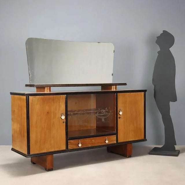 Vintage Italian-made sideboard with walnut veneer, hinged doors, open compartments and drawers, and a mirrored top. This...