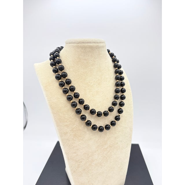 A refined continuous strand of polished black onyx beads, displaying the high-gloss finish characteristic of quality...