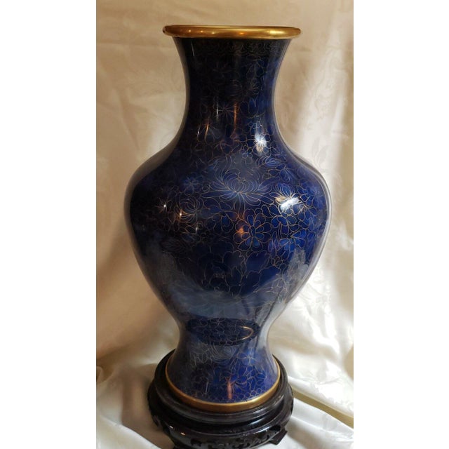 A Chinese Cloisonné Vase from the 20th century featuring blues and gold floral design on blue enamel. The rim and base are...