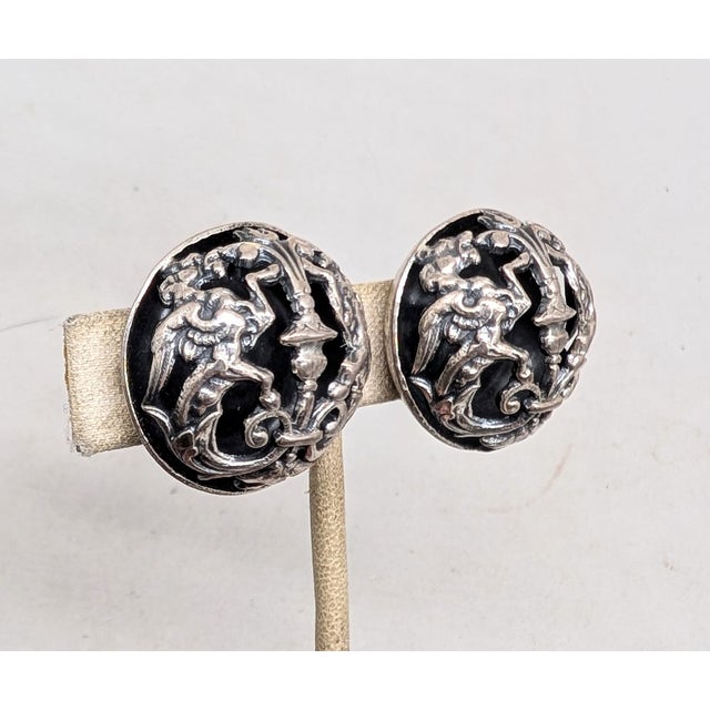 1972 silvertone round domed openwork fountain center with rearing griffins on either side clip earrings. Marked "NAPIER...