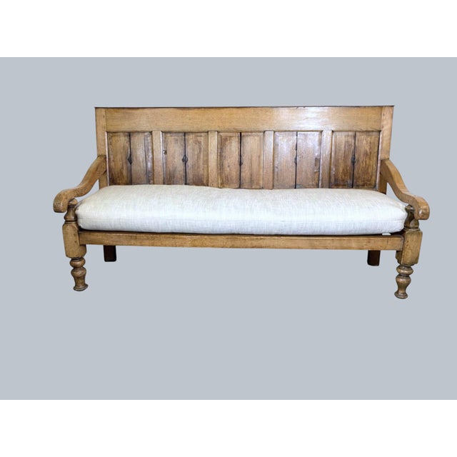 An English 1840 bench. Raised chamfered panels to the back. Dowl peg construction. Turned legs and arm support with loose...