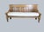 An English 1840 bench. Raised chamfered panels to the back. Dowl peg construction. Turned legs and arm support with loose...