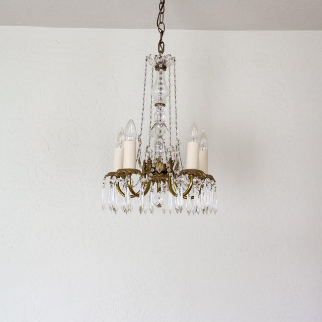 A petite French Louis XV-style crystal chandelier features a faceted central crystal column topped with a scalloped...