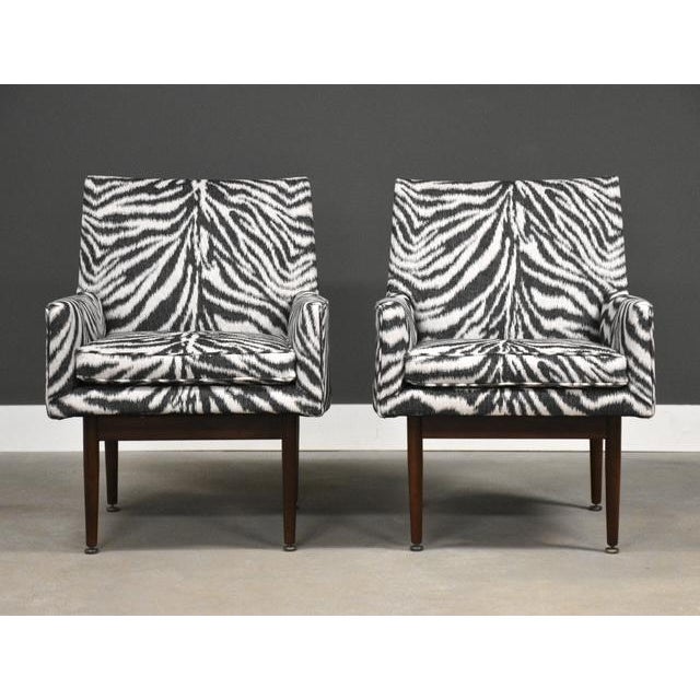 A pair of mid century modern lounge chairs with walnut legs that suspend the chairs designed by Jens Risom. Newly...
