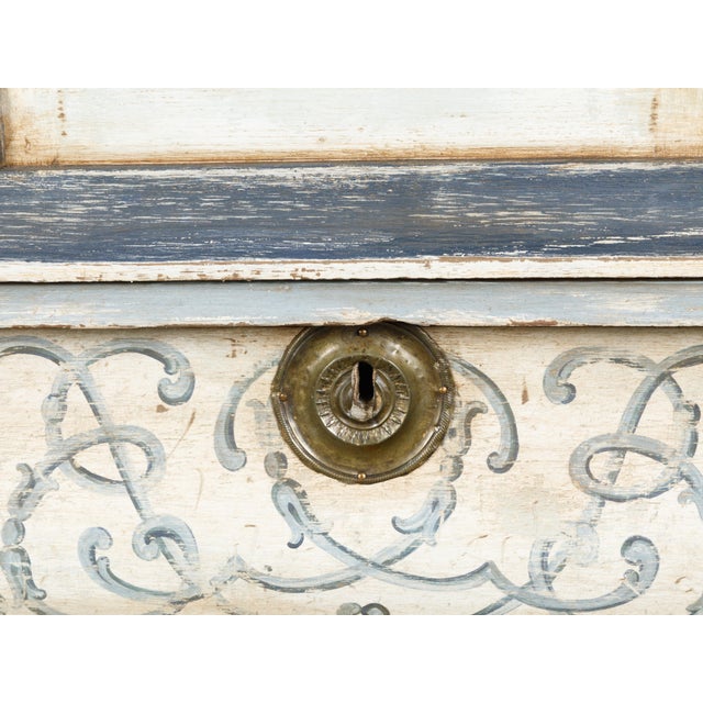A Dutch painted and carved wooden cabinet from the 19th century, with glass doors and bombé chest. Created in the...